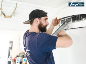 Taylor HVAC technician replacing the air filter on a mini-split AC system.