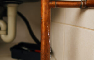 Cracked, leaking copper pipe under kitchen sink.